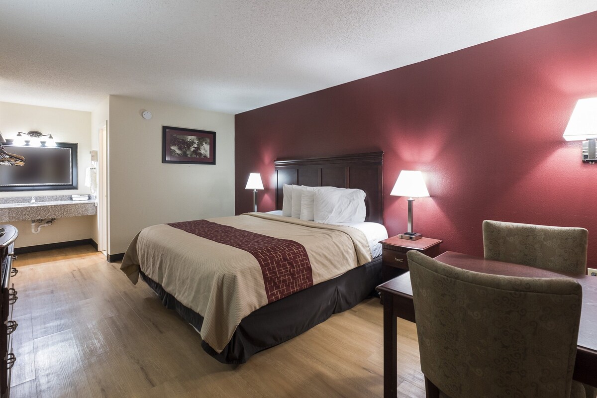A hotel room with a bed, bedside lamps, a desk, and a chair.