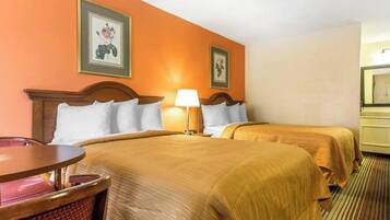 A hotel room with two beds, a round table, and a chair.