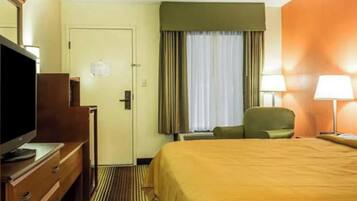 Una habitación de hotel con cama, televisión, escritorio y silla.