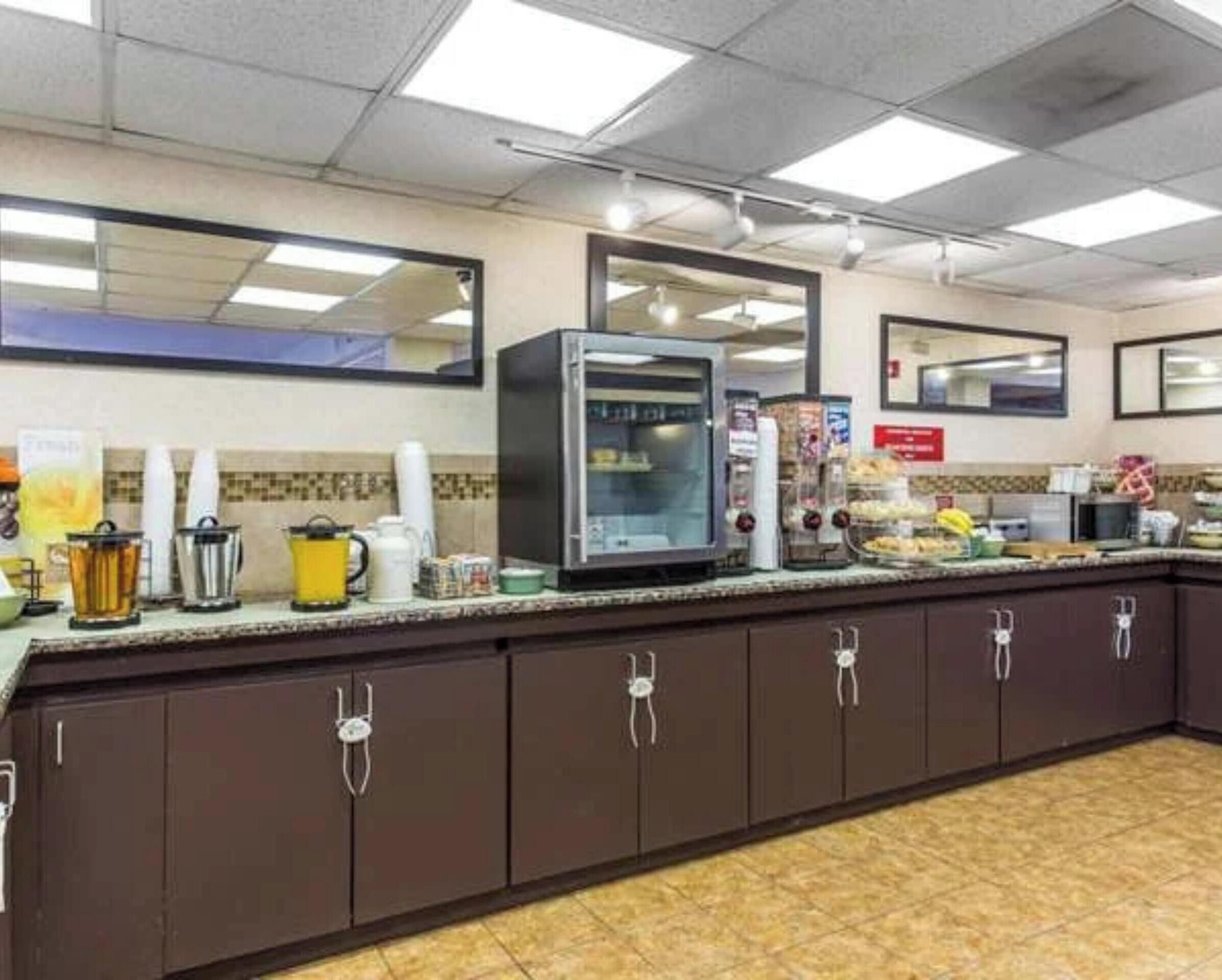 Zona de desayuno autoservicio con microondas, cafetera y diferentes alimentos en la barra.