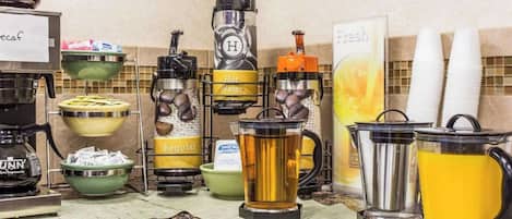 Un buffet proposant une variété de boissons, notamment de l’eau chaude, de l’eau ordinaire et différentes sortes de café.