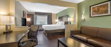 Ein Hotelzimmer mit Bett, Schreibtisch, Sessel, Sofa und einem Bild an der Wand.