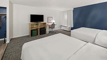 Une chambre d’hôtel avec deux lits, un bureau avec une chaise, une télévision, une lampe et une armoire.