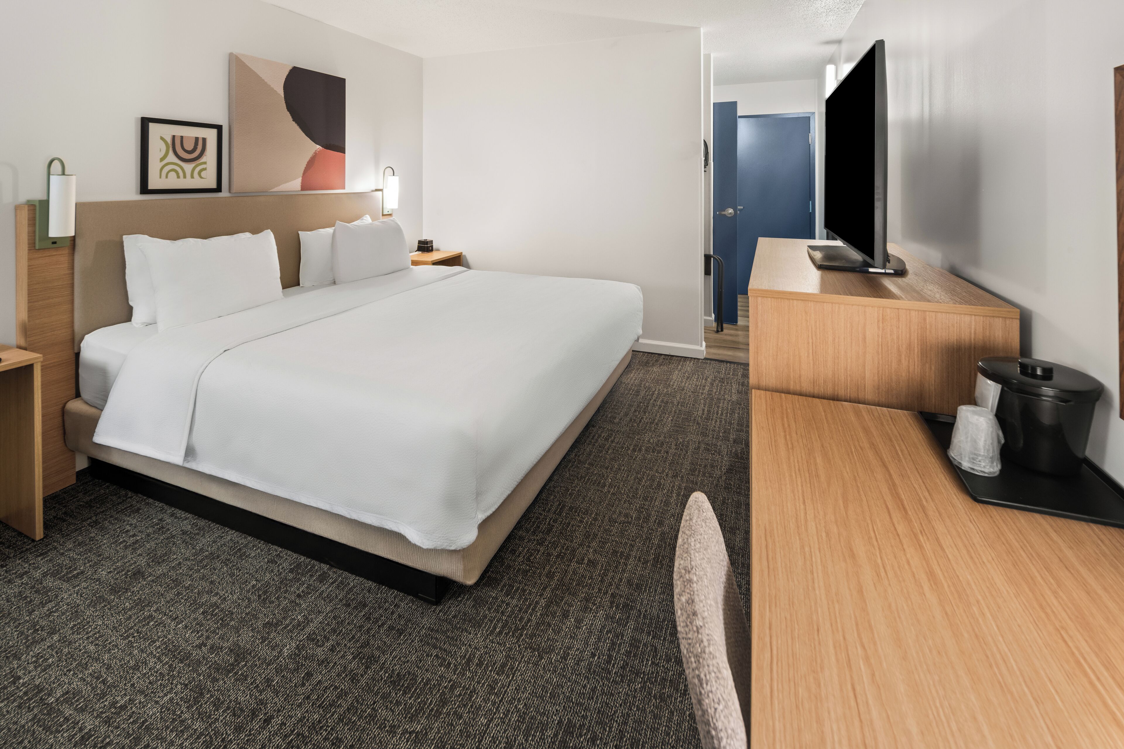 Una habitación de hotel con una cama grande, un escritorio, un televisor y una cafetera.