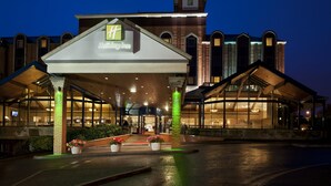 A Holiday Inn hotel with a modern architectural design, featuring a prominent entrance with a covered walkway and large windows.