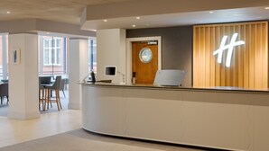 A modern reception desk with a wooden panel and a large illuminated 'H' sign.