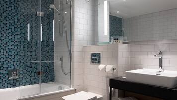 Un bagno moderno con cabina doccia in vetro, lavabo bianco e parete rivestita di piastrelle.