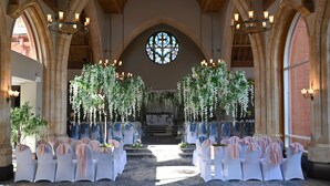 An aisle with white chairs and hanging floral decorations, leading to an altar.