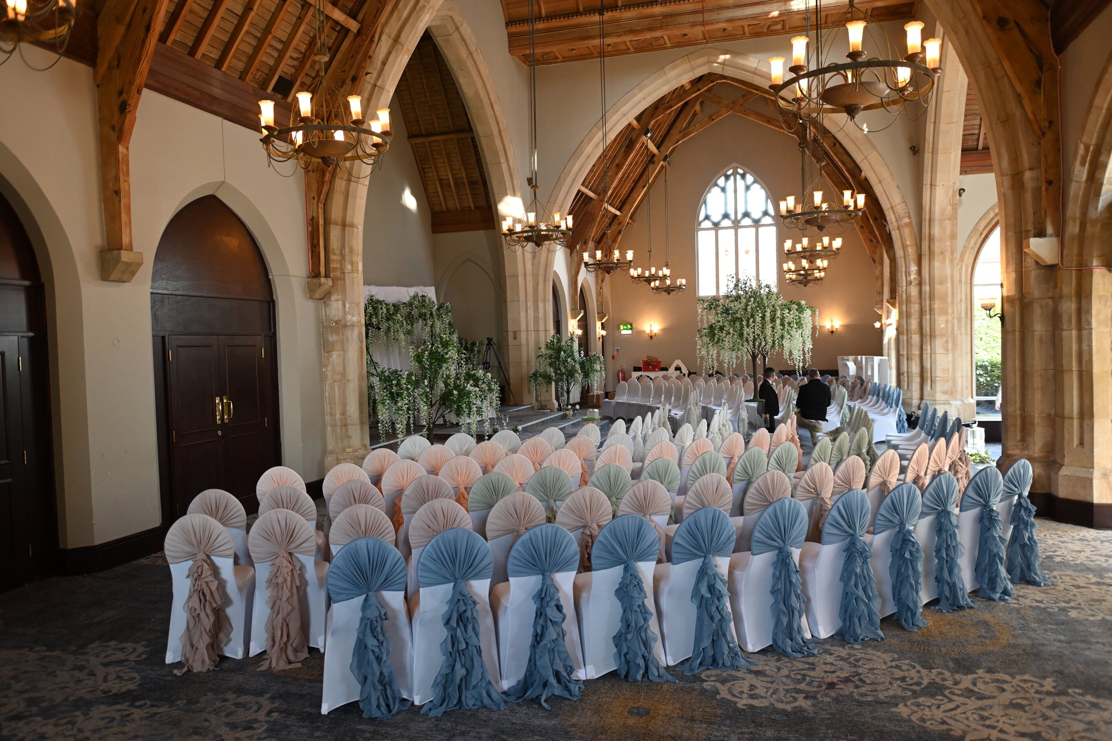 A banquet hall with rows of tables, chandeliers, and arched ceilings.