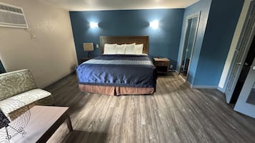 A hotel room with a bed, bedside table, lamp, and a ceiling fan.