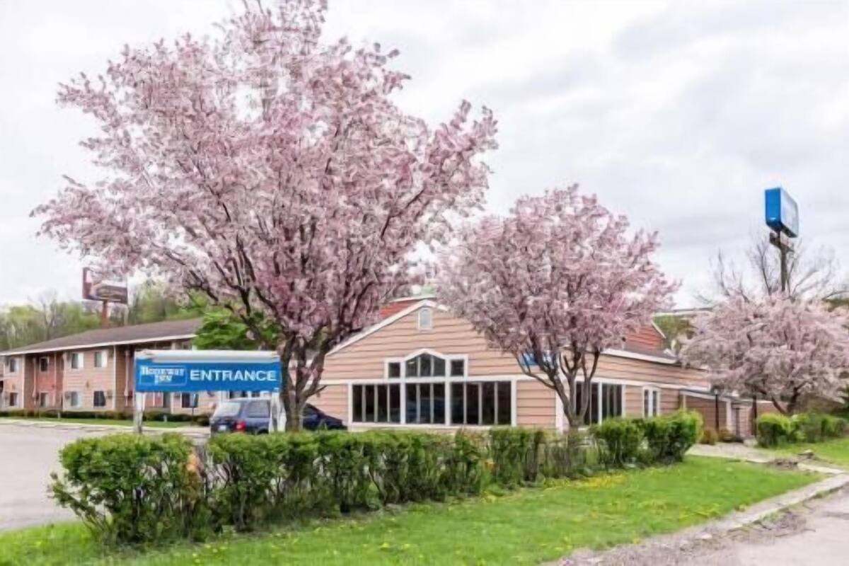 Een gebouw met een bord waarop 'Entree' staat en een parkeerplaats ervoor.