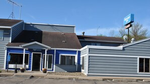 Un motel con fachada azul y gris, entrada visible y un letrero del 'Rodeway Inn'.