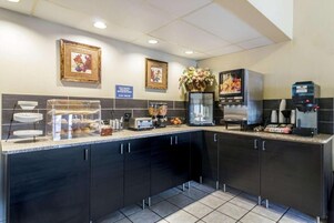 Una cocina moderna con cafetera, tostadora y una vitrina con pasteles.