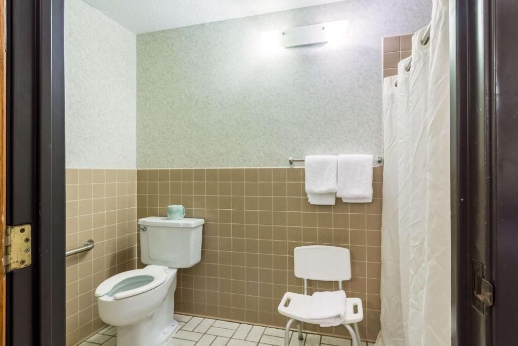 A bathroom with a toilet, a shower curtain, and a towel rack.