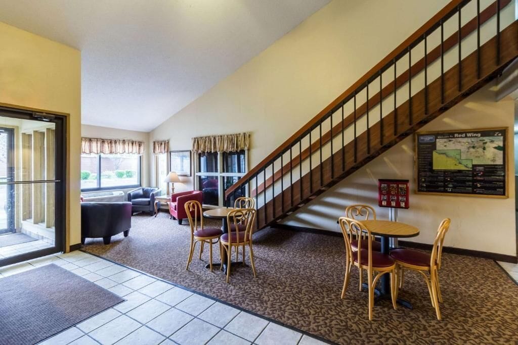 A hotel lobby with a staircase, seating area, and a map on the wall.