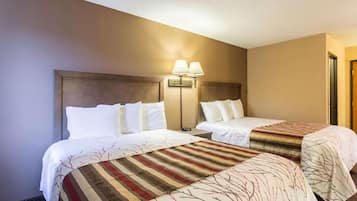 Una habitación de hotel con dos camas, una mesita de noche y una lámpara de pared.