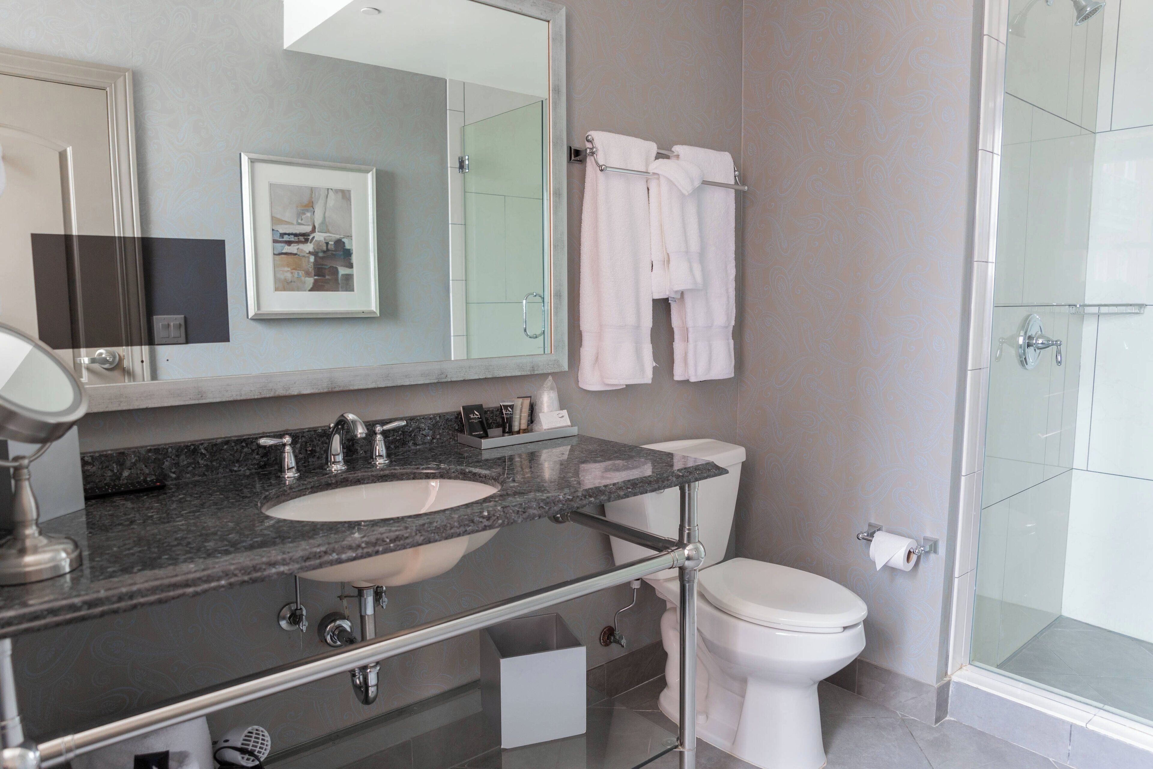A modern bathroom with a double sink, a toilet, and a glass shower enclosure.