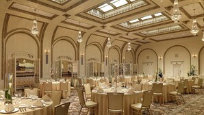 A banquet hall with round tables, chandeliers, and arched doorways. - Hotel Blackhawk, Autograph Collection (Davenport)