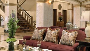 A spacious lobby with a grand staircase, a plush red sofa set, and a chandelier. - Hotel Blackhawk, Autograph Collection (Davenport)