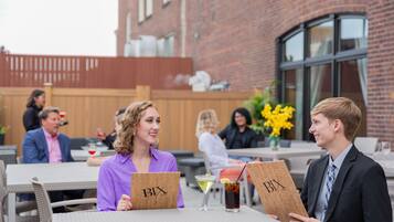 A group of people seated at an outdoor table with a drink and a menu.