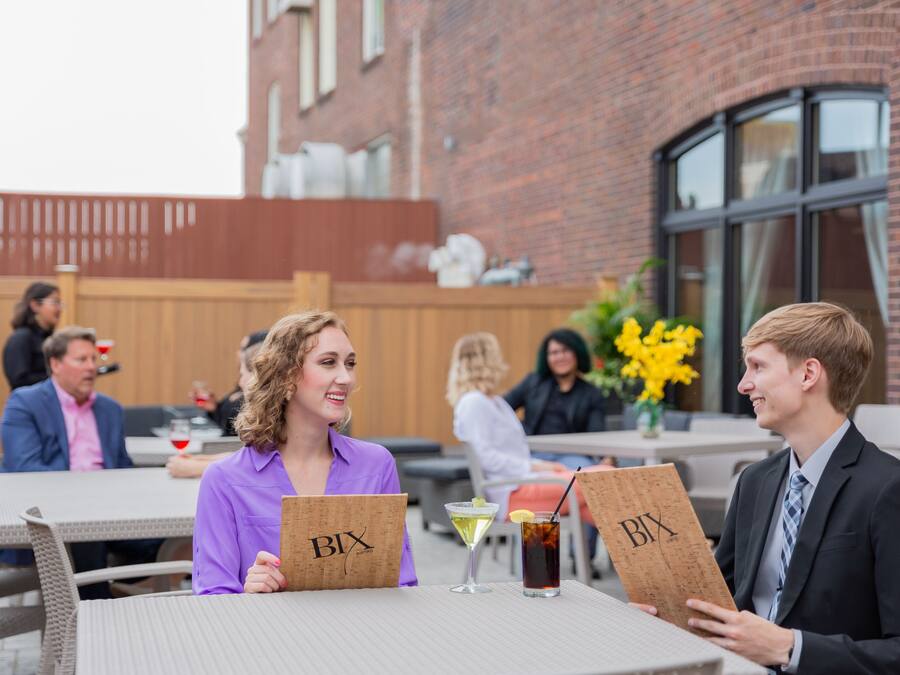 A group of people seated at an outdoor table with a drink and a menu.