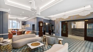 A spacious lobby with a modern design, featuring a large seating area, a grand piano, and a decorative wall with geometric patterns. - Commodore Hotel (London)