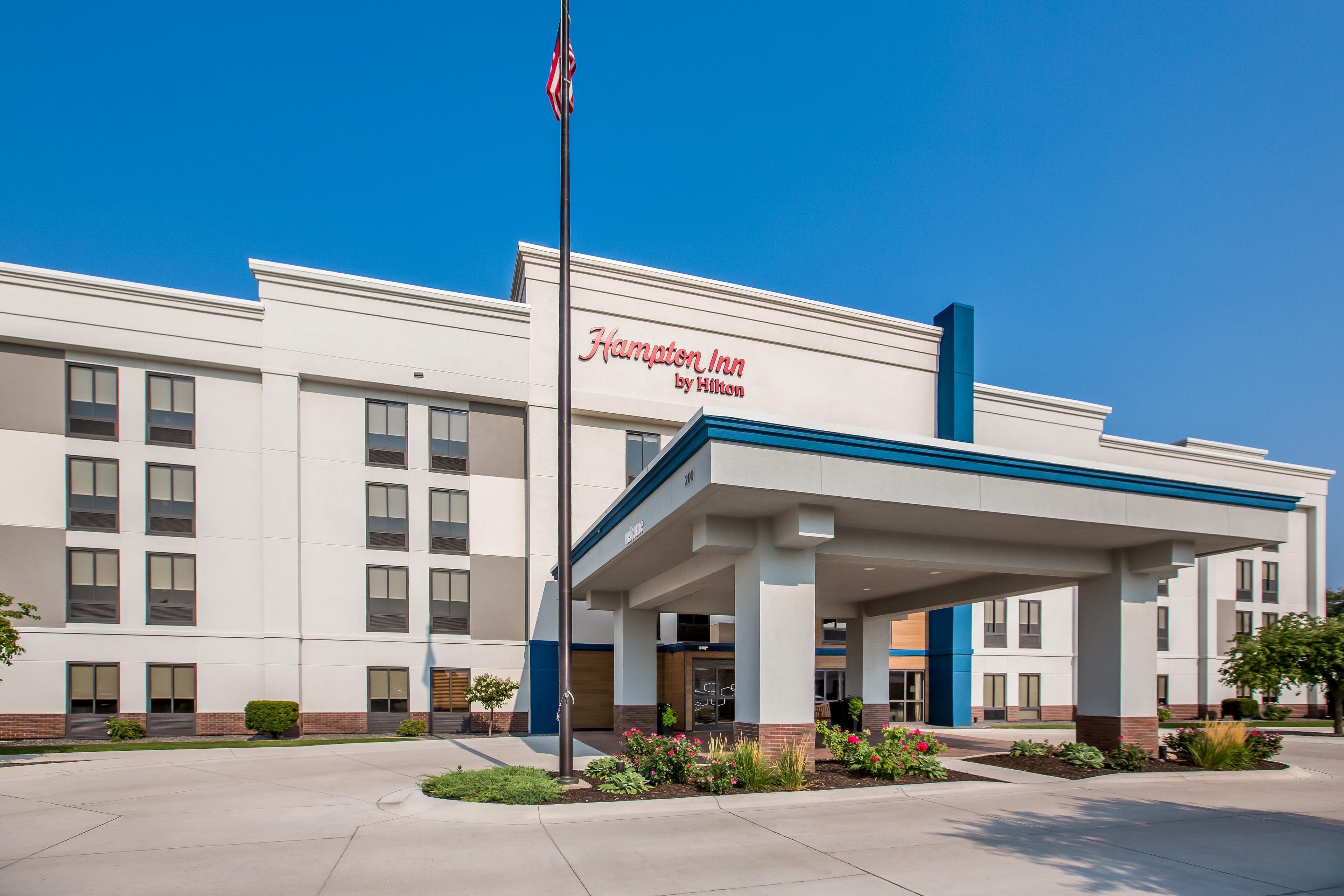 A Hampton Inn by Hilton hotel with a covered entrance and a flagpole.
