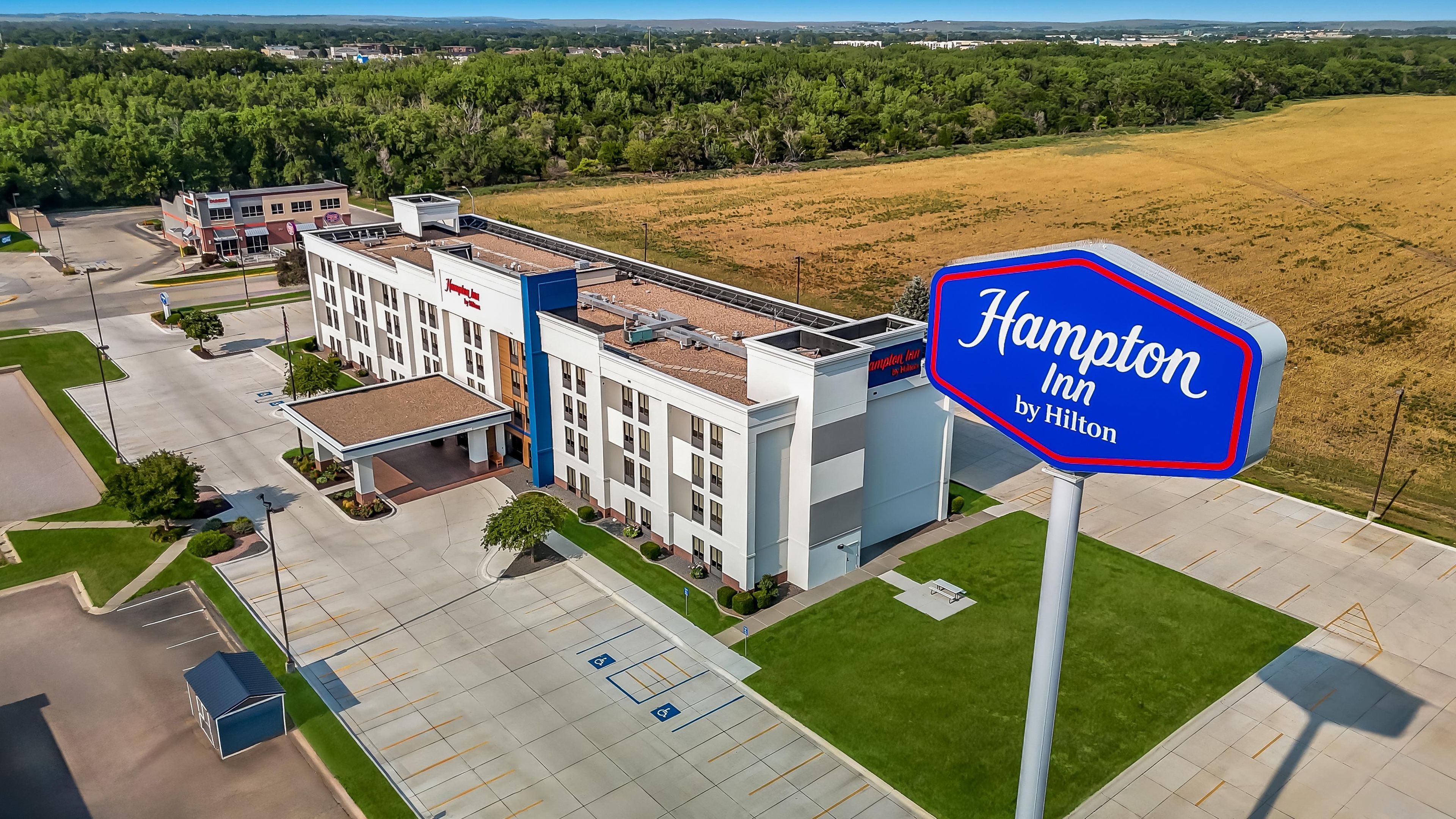 A Hampton Inn by Hilton hotel with a parking lot, a gas station, and a large sign.
