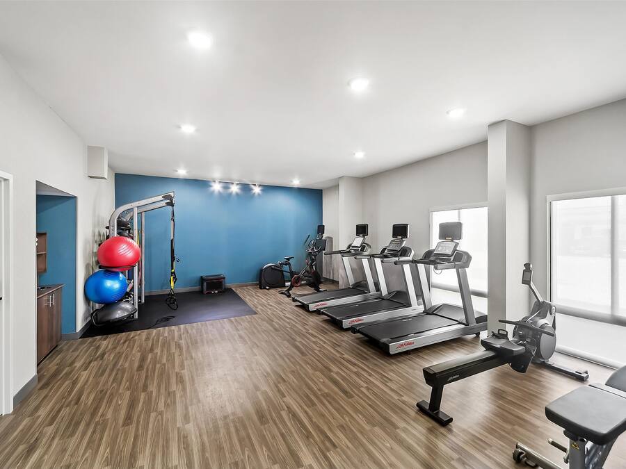 A gym with treadmills, elliptical machines, and exercise balls.