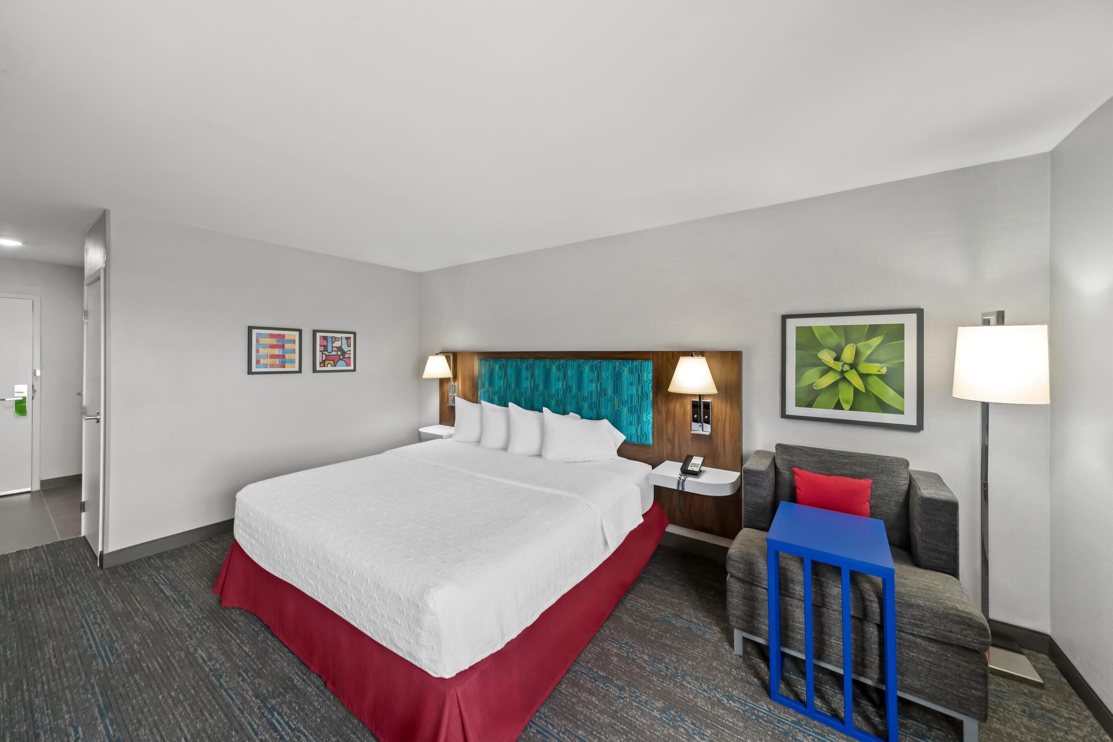 Une chambre d’hôtel avec un grand lit, un bureau, une chaise et une table de chevet.