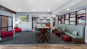 A modern hotel lobby with a reception desk, seating area, and a large window. - Hampton Inn North Platte (North Platte)