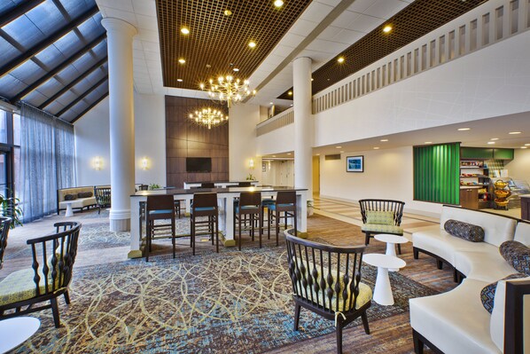 A spacious lobby with a high ceiling, a chandelier, seating areas, and a reception desk. - Holiday Inn Washington-Dulles International Airport by IHG (Sterling)