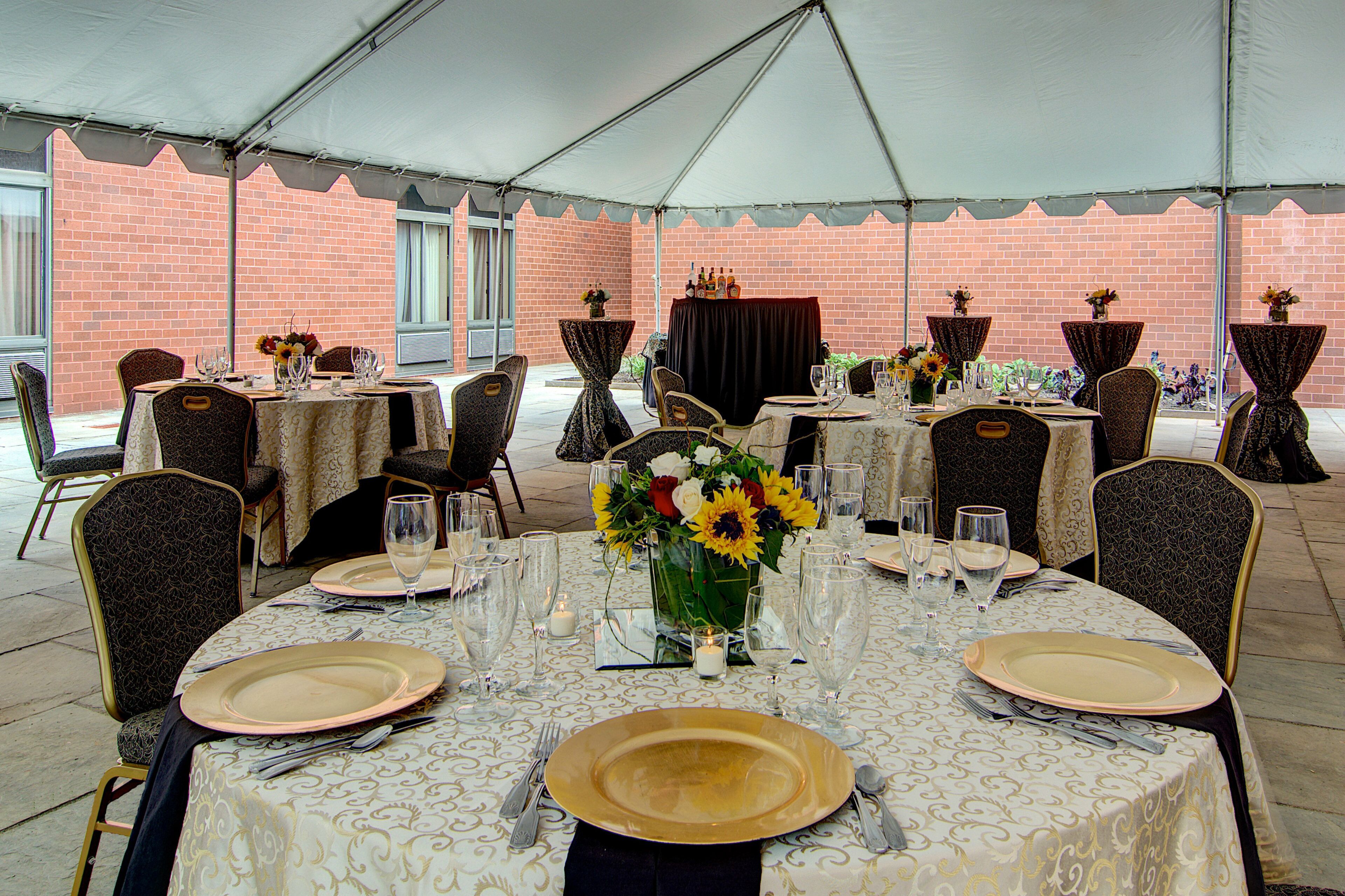 A tented outdoor dining area with tables set for a meal, featuring chairs and table settings.