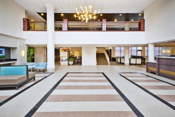 A spacious lobby with a central open area, a staircase, and a reception desk. - Holiday Inn Washington-Dulles International Airport by IHG (Sterling)