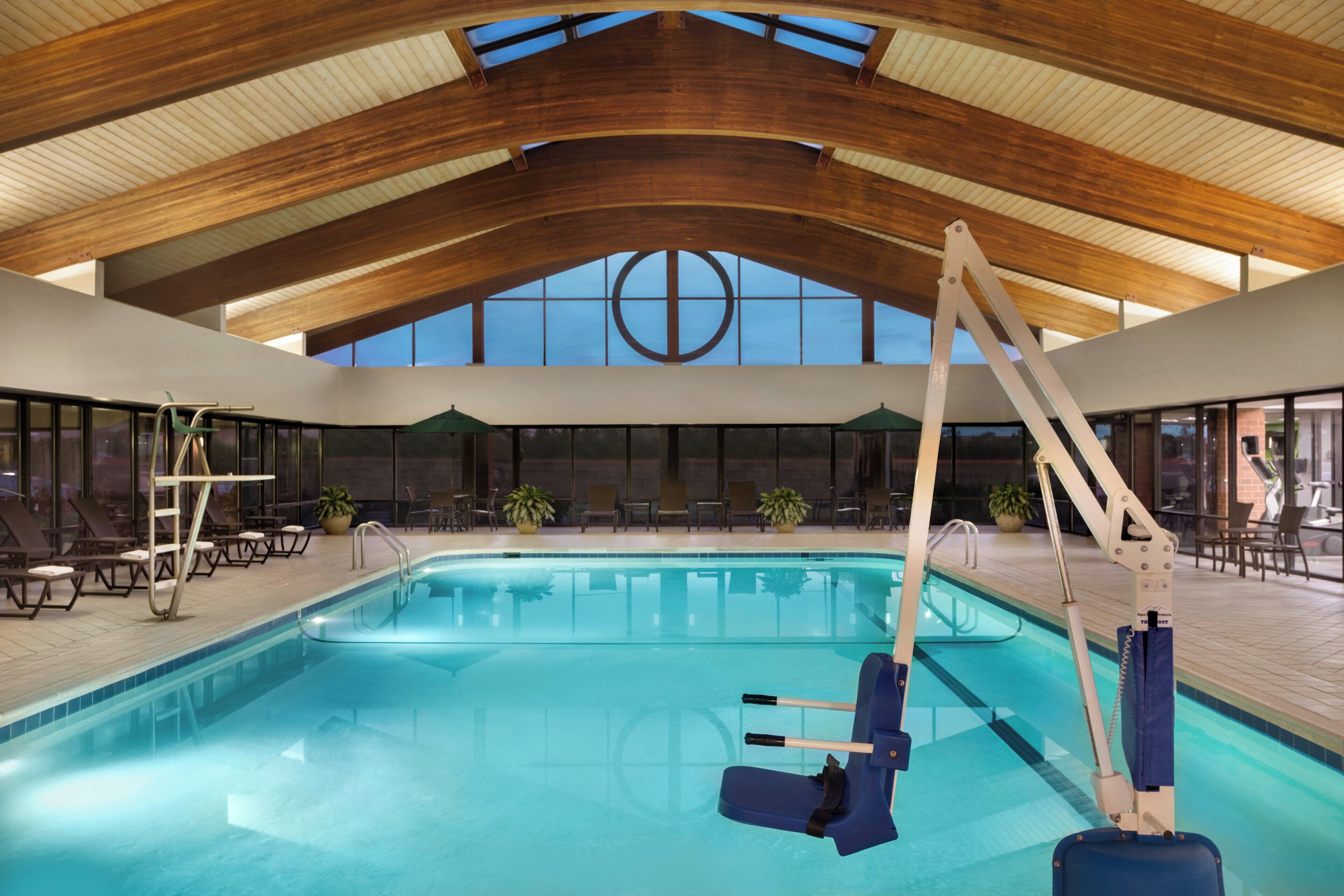 Una piscina interior con techo alto, sillas de descanso y puesto de socorrista.