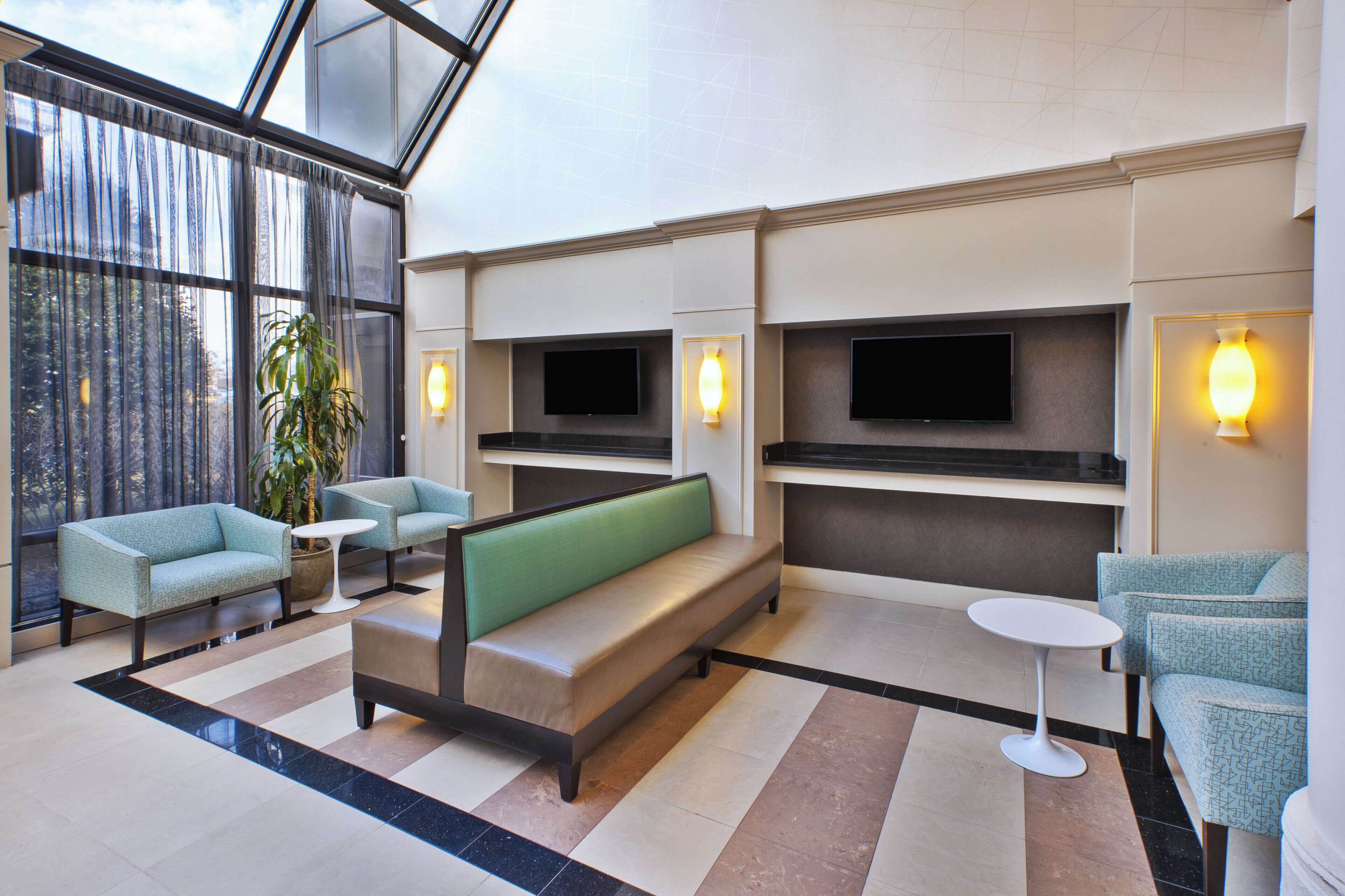 Een moderne lobby met zithoeken, een groot raam en een flatscreen televisie aan de wand.