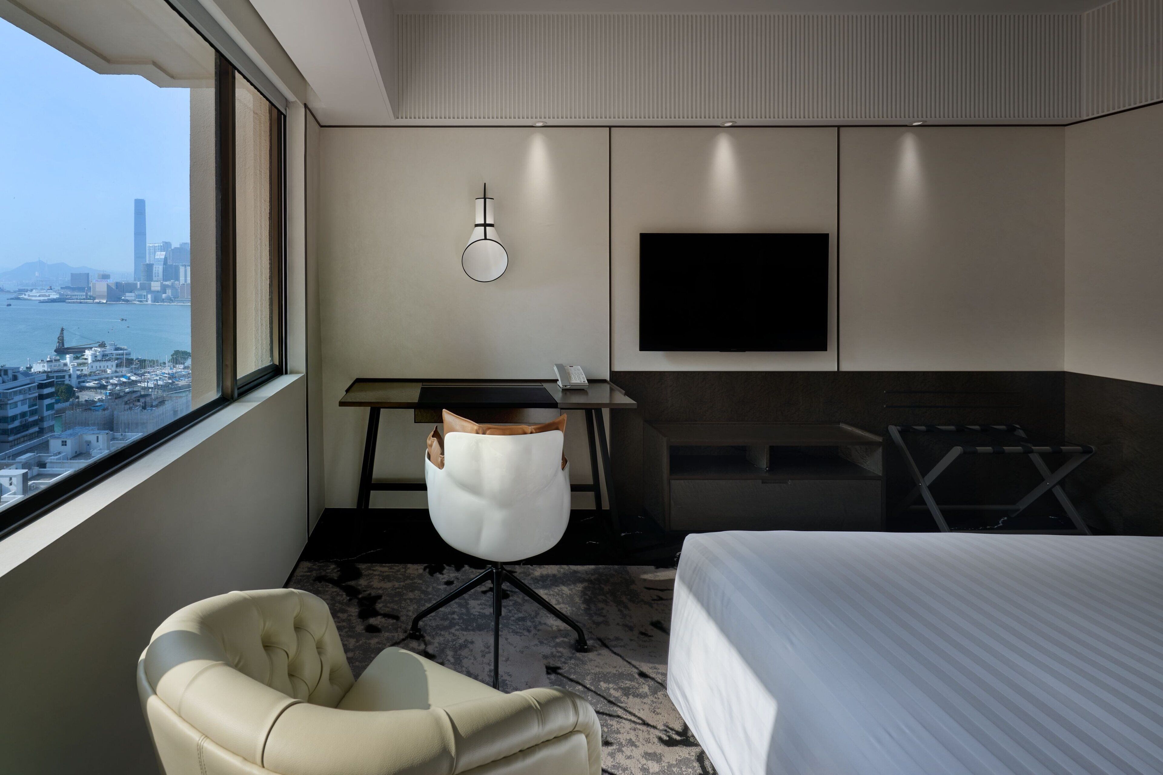 Ein Hotelzimmer mit Bett, Schreibtisch, Stuhl, Fernseher und Blick auf die Stadt.