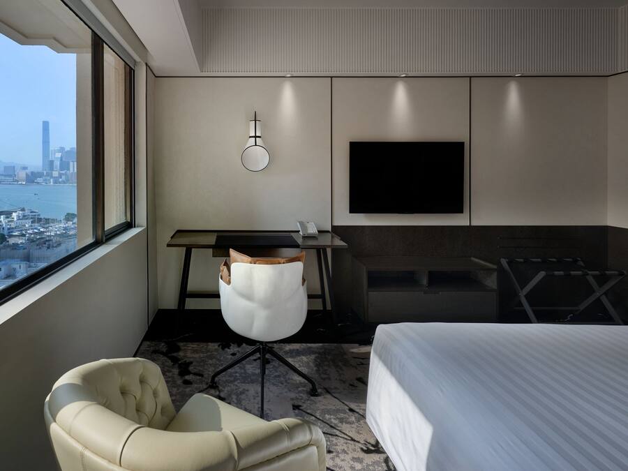 Ein Hotelzimmer mit Bett, Schreibtisch, Stuhl, Fernseher und Blick auf die Stadt.