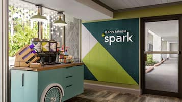 A teal-colored cart with coffee-making equipment and a sign that reads "It only takes a spark."