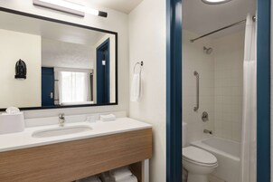 A bathroom with a white sink, mirror, and a shower with a curtain.