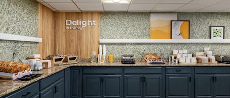 A modern kitchen with dark blue cabinets, a wooden accent wall, and a tiled backsplash.