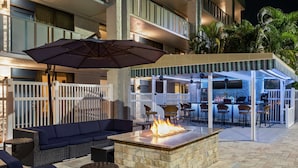 Eine Terrassenanlage im Freien mit Feuerstelle, Sitzgelegenheiten und einer Bar.