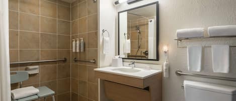 A modern bathroom with a shower, toilet, sink, and handrails.