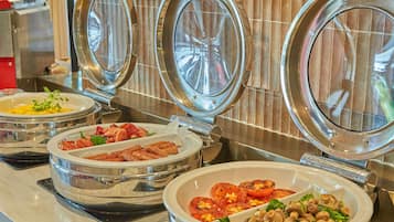 Een buffet met diverse gerechten, zoals eieren, spek, tomaten en champignons.