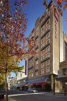 Un hotel con fachada de ladrillo, varios balcones y cielo despejado.