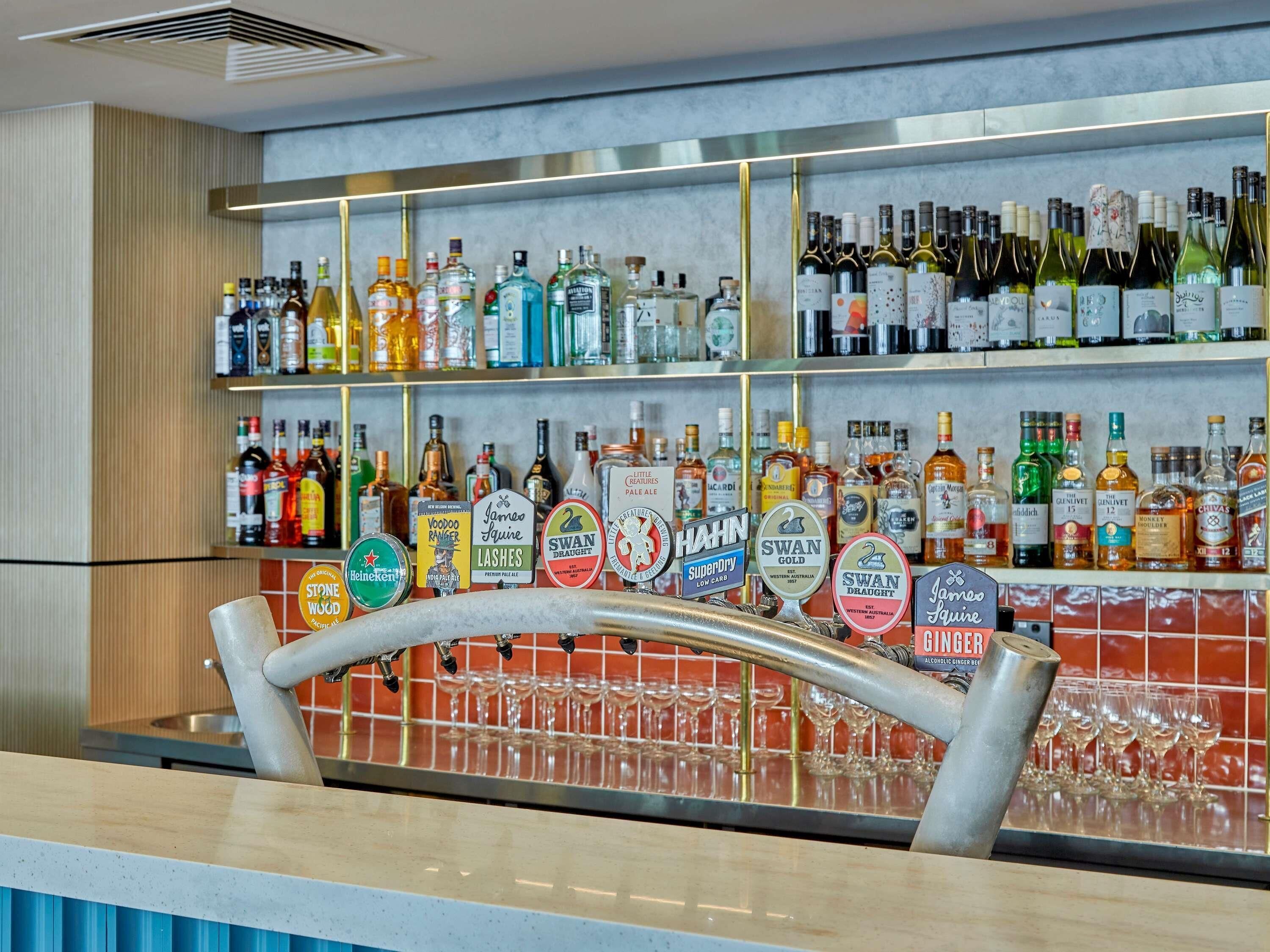 A bar area with shelves stocked with various alcoholic beverages and a tap bar with multiple taps.