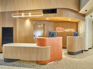 A hotel reception area with a wooden finish, a reception desk, a door, and a security camera.