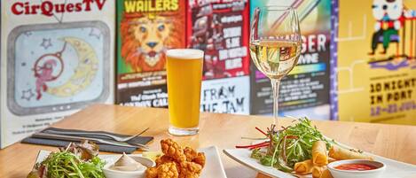 Una mesa con dos platos de comida, una jarra de cerveza y un cartel de menú al fondo.