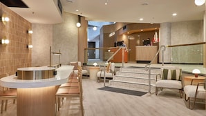 A modern hotel lobby with a reception desk, seating area, and a staircase leading to an upper level. - ibis Perth (Perth)