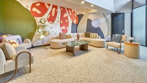 A modern lounge with a sofa, armchairs, a coffee table, and a unique abstract wall mural. - ibis Perth (Perth)